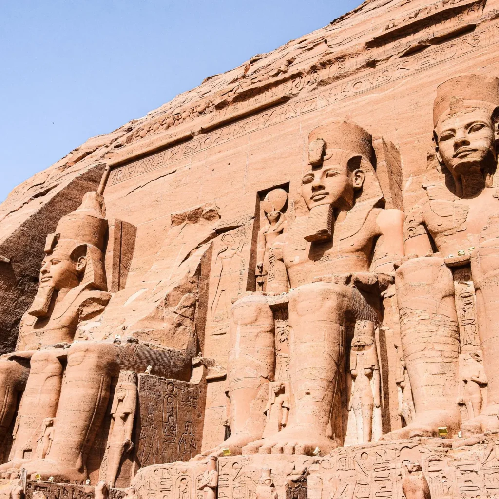 Majestic sandstone statues at the Temple of Ramesses II under a clear blue sky.